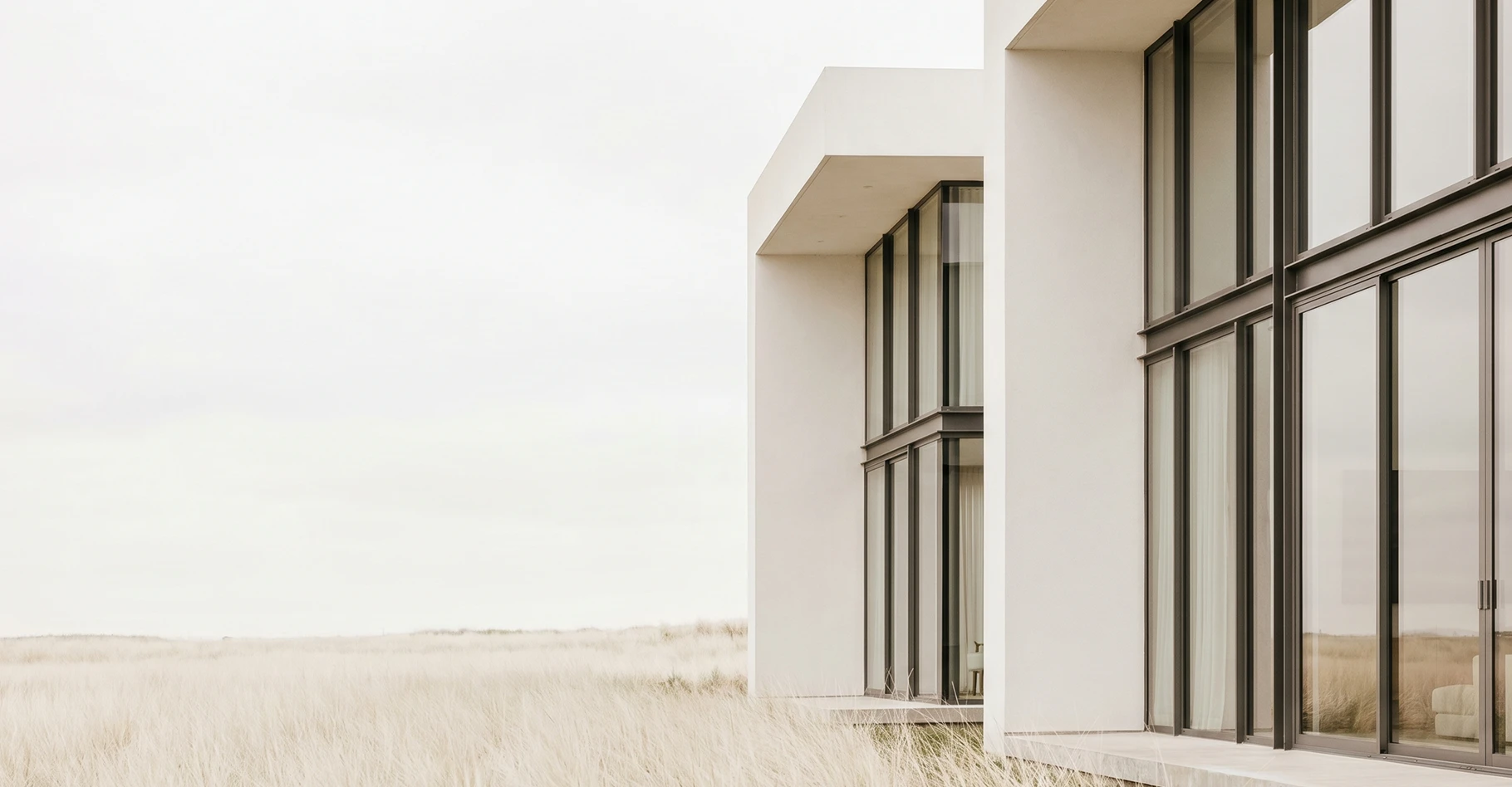 Modern white villa with floor-to-ceiling windows in a meadow
